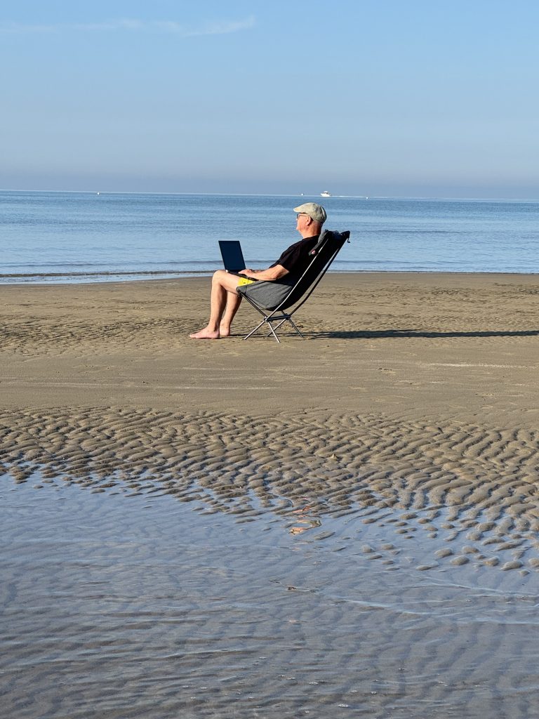 Der Autor Jörg Manz aus der entfernten PErspektive auf einem Strandsessel auf der Sandbank bei Niedrigwasser